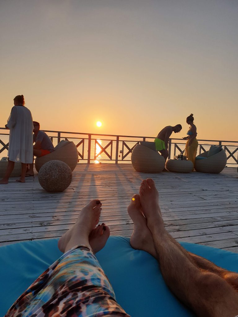 IO ED ALAN SDRAIATI AL BAR DEL RESORT SU UN MOLO AL TRAMONTO